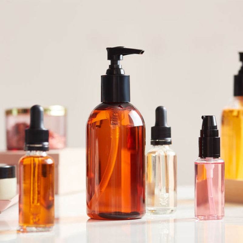 Composition of colorful skincare oils in different sized bottles on table.
